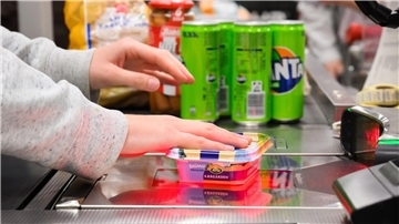 Eine Kassiererin scannt Lebensmittel an der Kasse eines Supermarktes.