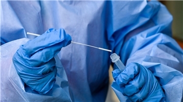 Eine Krankenschwester steckt ein Abstrichstäbchen in die Flüssigkeit eines Corona-Schnelltests.