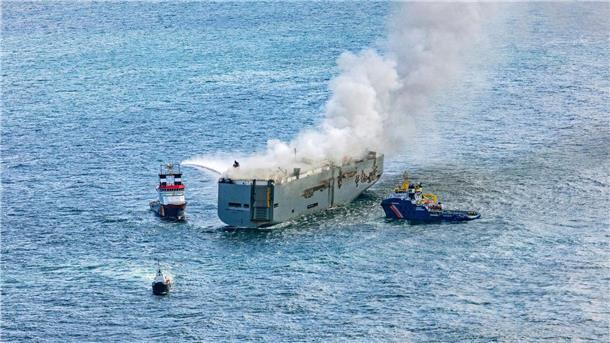 Weshalb brennende E-Autos so schwer zu löschen sind Eine Luftaufnahme zeigt einen deutschen Notschlepper(l), der das Feuer auf dem brennenden Frachter „Fremantle Highway“ bekämpft.