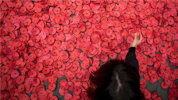 Eine Person hebt eine Papiermohnblume auf, die während einer Kundgebung gegen den Gaza-Krieg vor dem spanischen Außenministerium in Madrid auf dem Boden liegt. 