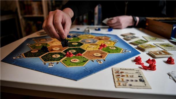 Hauptsache Spielen Eine Person spielt das Brettspiel Siedler von Catan.