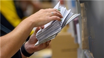 Eine Person hält mehrere Briefe in der Hand. 