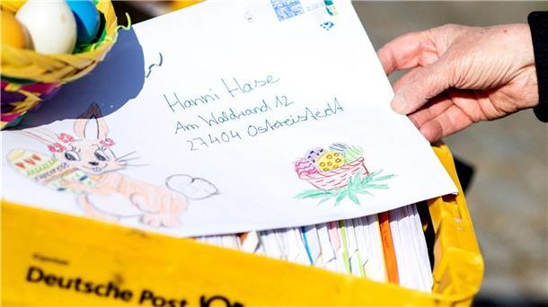 Eine Mitarbeiterin im Osterpostamt hält einen Brief, den ein Kind an den Osterhasen Hanni Hase geschrieben hat, in den Händen.