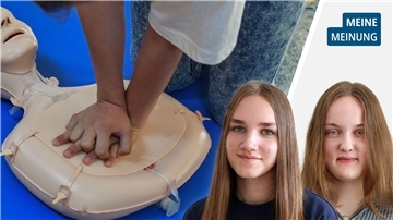 Porträt zweier Schülerinnen mit langem Haar, neben einem Dummy zum Üben der Reanimation.