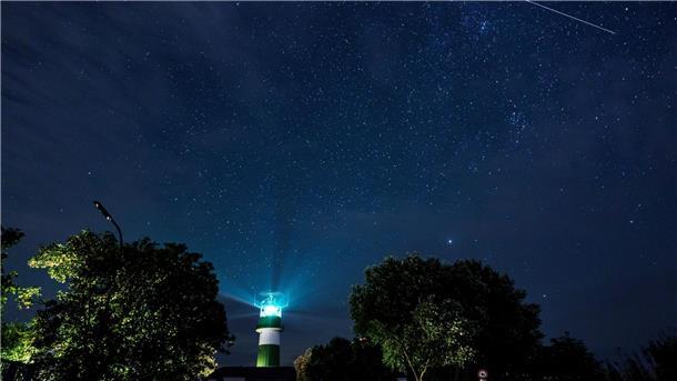 Eine Sternschnuppe zieht über dem Leuchtturm Bülk am Ufer der Ostsee ihre Bahn.