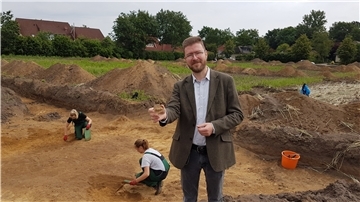 Alte Siedlung im Neubaugebiet in Bülstedt Eine Tonscherbe könnte einen Hinweis darauf geben, wann hier Menschen gesiedelt haben. Kreisarchäologe Dr. Stefan Hesse präsentiert das frisch freigelegte Fundstück an der Grabungsstätte am Rande Bülstedts.