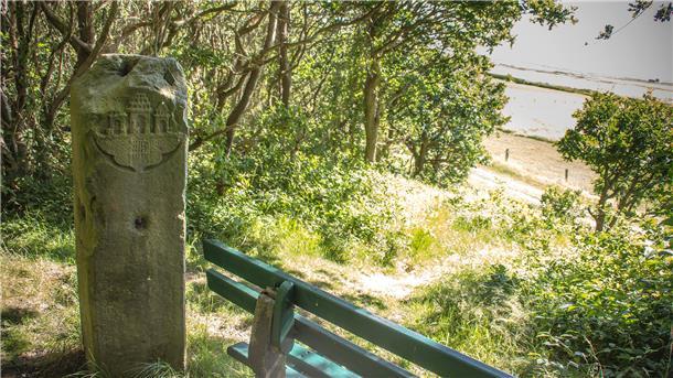 Am Weserdeich entlang des Wattenmeers bis in einen kleinen Wald bei Berensch unscheinbare Bank neben einer ebenso unscheinbaren Sandsteinsäule