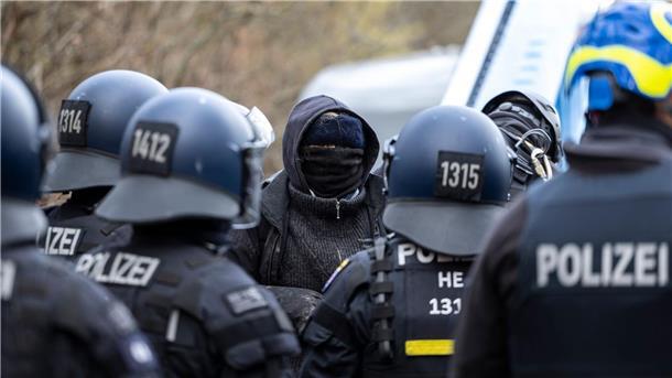 Eine vermummte Person steht im Fechenheimer Wald der Polizei gegenüber.