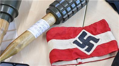 Sichergestellte Handgranaten und Materialien, darunter auch eine Armbinde mit einem Hakenkreuz, liegen bei einem Pressetermin im LKA Brandenburg auf einem Tisch nach einer Razzia gegen die Neonazi-Gruppe "Freie Kräfte Prignitz".