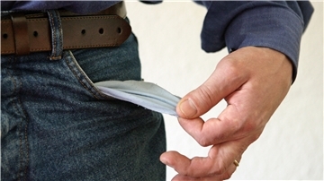 Ein Mann zieht kehrt die leere Innenseite seiner Jeans nach außen. 