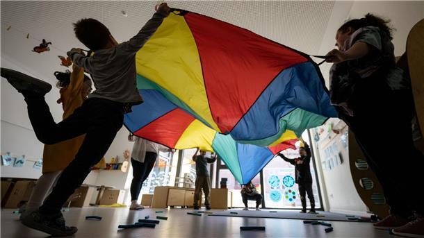 Bild von Kindern mit Erzieherinnen, die gemeinsam ein Bewegungsspiel spielen