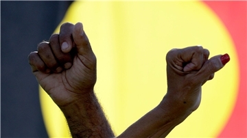 Ein Mann und eine Frau verschränken die Arme vor einer Aborigines-Flagge während einer Kundgebung der Bewegung „Black Lives Matter“ in Sydney (Symbolbild). Der „Sydney Morning Herald“ hat sich für seine Berichterstattung zum Myall-Creek-Massaker entschuldigt.