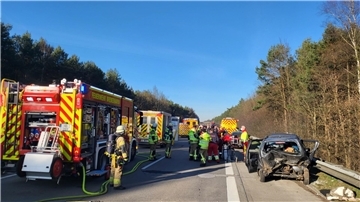 Ein verunfalltes Auto steht neben der Leitplanke, auf der Autobahn stehen Feuerwehr und Rettungswagen.