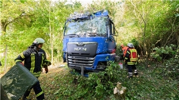 Einsatzkräfte der Feuerwehr stehen neben dem verunfallten Lkw an der Bundesstraße B3.