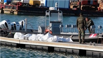 Einsatzkräfte der tunesischen Küstenwache im Hafen von Sfax neben zugedeckten Leichen auf einem Steg (Archivbild).