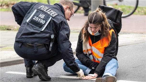 „Letzte Generation“: Die Klimaaktivisten, die jetzt einen guten Anwalt brauchen Einsatzkräfte lösen den Klebstoff, mit dem sich eine Aktivistin der Letzten Generation an der Straße festgeklebt hat. Die Klimaaktivisten blockieren so immer wieder den Verkehr.