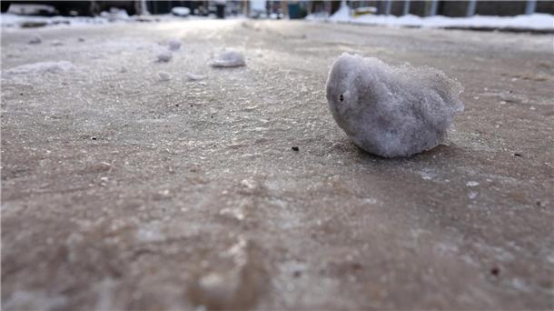 Gefahr für glatte Straßen wegen gefrierender Nässe Eisklumpen liegen auf einer vereisten Straße.