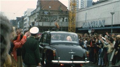 Foto stammt aus den 60er Jahren und zeigt ein Auto, umsäumt von jubelnden Menschen. 