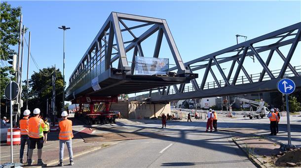 Eine große Stahlbrücke wird an ihren Platz gefahren.