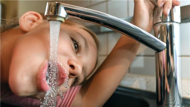 Kind trinkt am Wasserhahn