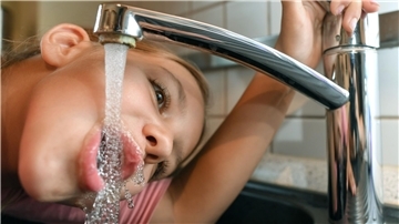 Kind trinkt am Wasserhahn