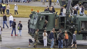 Jugendliche schauen sich ein Militärfahrzeug an.