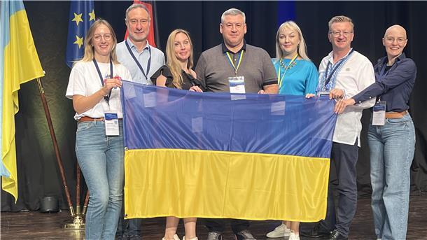 Wie der OOWV ukrainischen Städten bei der Wasserversorgung hilft Gruppenfoto mit sieben Menschen, Frauen und Männern, die die Ukraine-Flagge in den Händen halten.