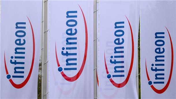 Fahnen mit dem Logo von Infineon wehen vor dem Werk des Chipherstllers in Dresden im Wind.