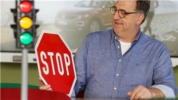 Fahrlehrer Horst Wintgen sitzt mit Ampel und Verkehrsschild im Übungsraum seiner Fahrschule.