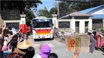 Familienmitglieder und Freunde von Häftlingen stehen vor dem Insein-Gefängnis in Yangon, als ein Bus mit Freigelassenen vom Gelände fährt.