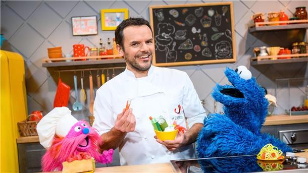 Mehr als 23 Hingucker fürs Fernsehjahr 2023 Fernsehkoch Steffen Henssler zwischen den Puppen „Gonger“ (l) und „Krümelmonster“ am Film-Set.