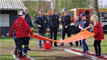Feuerwehrdezernent Stadtrat Peter Skusa schaut sich zusammen mit dem Jugendfeuerwehrwart Jan Haucke und den Organisatoren Nathalie Zander und Thies Renken gespannt eine Station der Kinderflamme an.