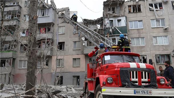Feuerwehrleute arbeiten daran, ein Feuer zu löschen, während sie nach einem Raketenangriff nach möglichen Opfern suchen.