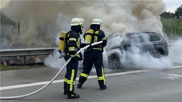 Das Foto zeigt Feuerwehrleute beim Löschen des brennenden Fahrzeugs.  