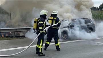 Das Foto zeigt Feuerwehrleute beim Löschen des brennenden Fahrzeugs.  