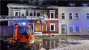 Feuerwehrleute löschen von einer Drehleiter aus ein Mehrfamilienhaus in Essen.
