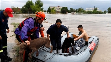 Feuerwehrleute mit einem Schlauchboot evakuieren Menschen und ihre Hunde aus überfluteten Gebäuden.