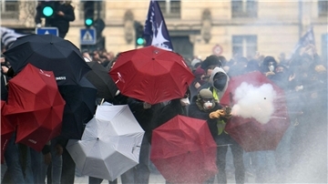 Feuerwerkskörper werden abgeschossen, Menschen verstecken sich hinter Regenschirmen: Proteste in Nantes.