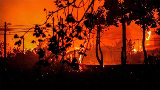 Zahl der Toten bei Waldbränden in Chile steigt auf 112 Flammen und Rauch sind zu sehen, als Häuser während eines Waldbrandes in Chile niederbrennen.