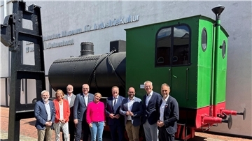 Eine Gruppe von Erwachsenen stehen vor einer alten Lokomotive.