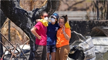 Frauen umarmen sich in den Trümmern eines vom Feuer zerstörten Hauses in Lahaina auf Hawaii.