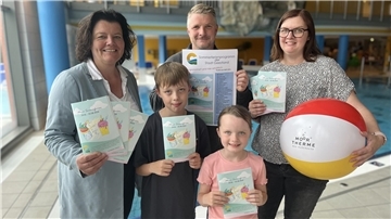 Zwei Frauen, ein Mann und zwei Kinder stehen in einem Schwimmbad.