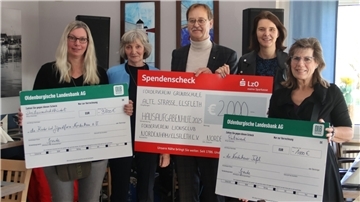 Vier Frauen und ein Mann mit Spendenschecks
