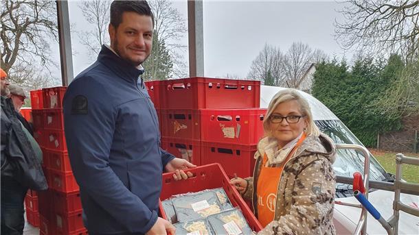 Ein Mann und eine Frau halten eine Kiste mit eingeschweißten Essen.