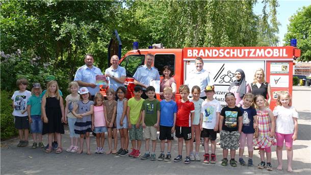 Kinder der Kita Naseweis zusammen mit ihren Erzieherinnen und Offiziellen vor dem Brandschutzmobil