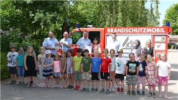 Kinder der Kita Naseweis zusammen mit ihren Erzieherinnen und Offiziellen vor dem Brandschutzmobil