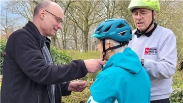 Fridtjof Gerritsma hilft bei der Einstellung des Fahrradhelms.