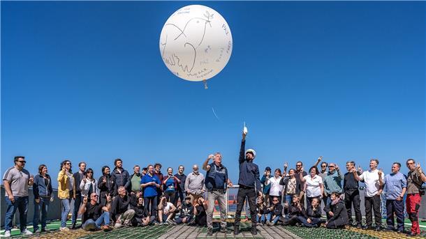 Das AWI und Russland: Eiszeit in der Wissenschaft Mehrere Menschen stehen zusammen und deuten in Richtung Himmel. Dort fliegt ein großer weißer Luftballon.