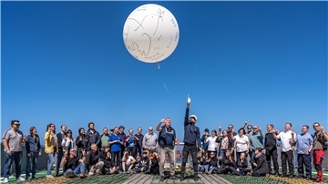 Das AWI und Russland: Eiszeit in der Wissenschaft Mehrere Menschen stehen zusammen und deuten in Richtung Himmel. Dort fliegt ein großer weißer Luftballon.