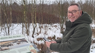 Friedrich Zittlosen ist beim Kultur- und Heimatverein Burg zu Hagen für das Königsmoor verantwortlich. Mit seinem Smartphone ruft er einen QR-Code am Rundweg die Geschichte von Piepenbrinks Hochszeit auf.